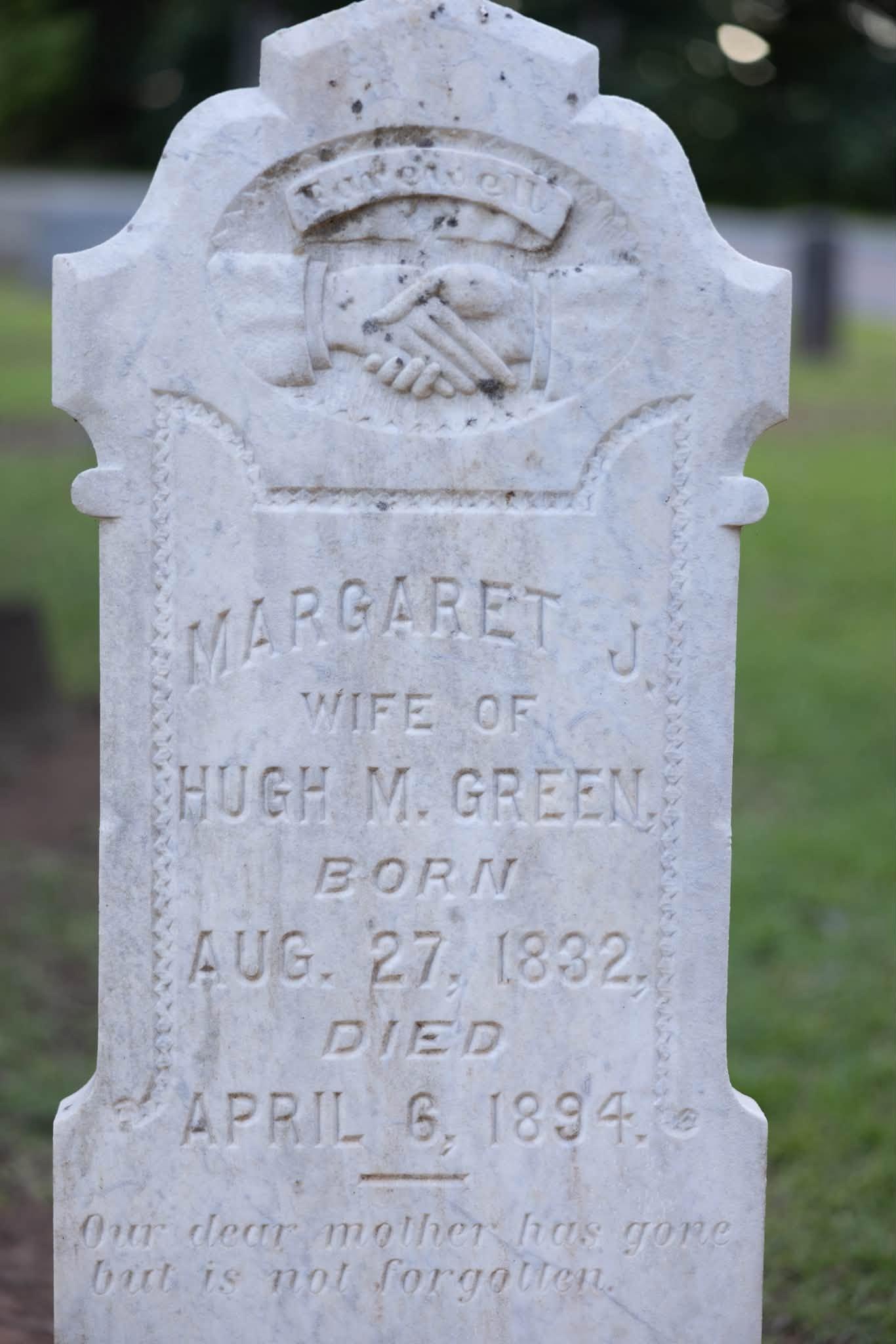 Weathered marble marker of Margaret J., wife of Hugh M. Green, 1832–1894, carved with clasped hands